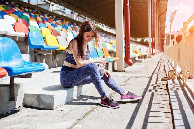 Gorgeous young fit woman sitting on a chair in the stadium