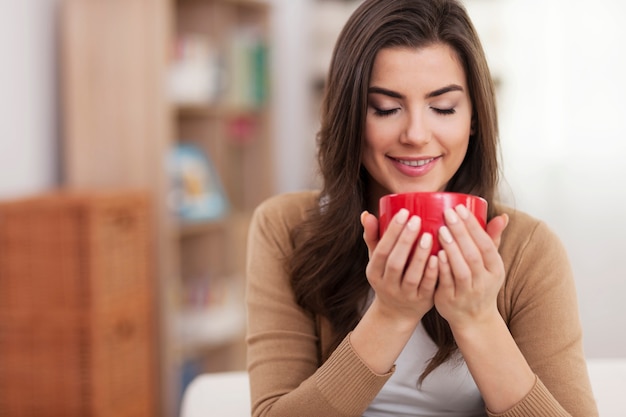 Gorgeous young woman relaxing with cup of coffee at home