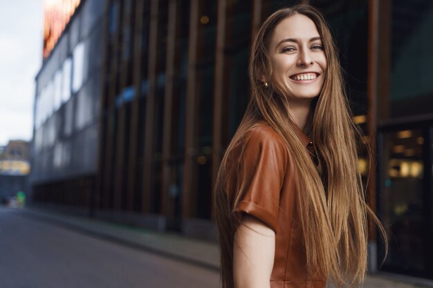 Gorgeous young woman smiling at camera, turning behind and smiling.