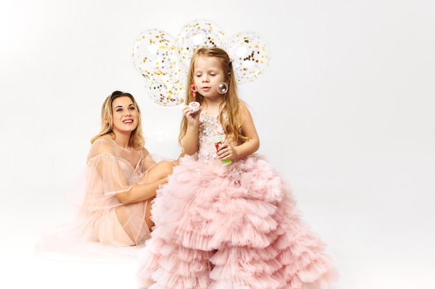 Free photo gorgeous young woman wearing low neck strapless dress celebrating birthday with her daughter