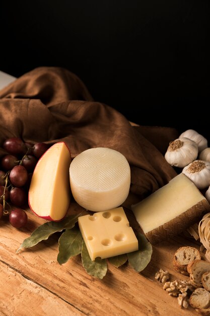 Gouda, parmesan and emmental cheese with ingredients over wooden surface