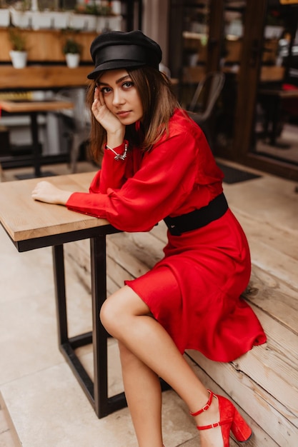 Free photo graceful brownhaired woman with expressive look gently touches her face girl with fine facial features shy and romantic posing for snapshot