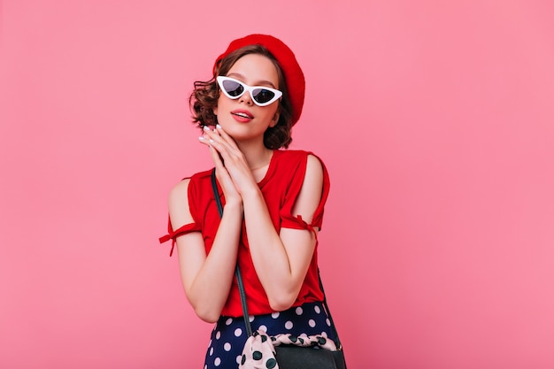 Graceful pale girl in french beret standing. Optimistic brunette woman in sunglasses posing.