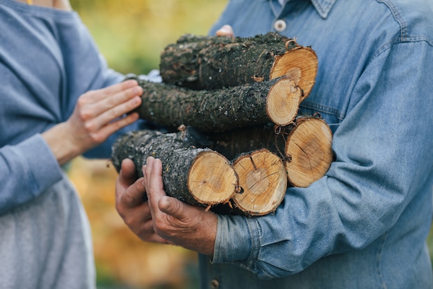 Free photo grandfather with granddaughter on a yard with firewood in hands