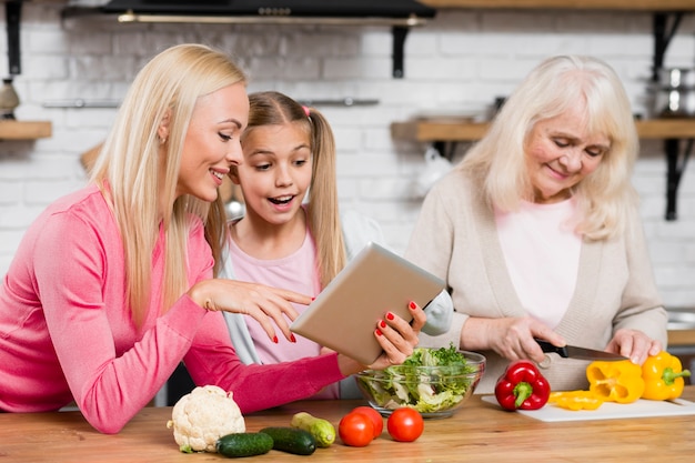 Grandma is cooking and women are using the tablet