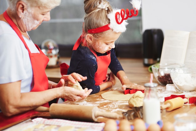 Grandma teaching her grandchild how to bake 
