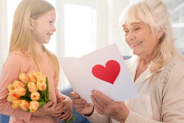 Free photo grandma with flowers and greeting card from girl