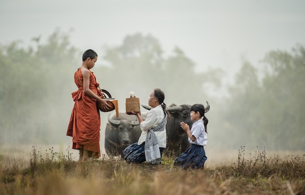 Grandmother and grandson offer food to the novices