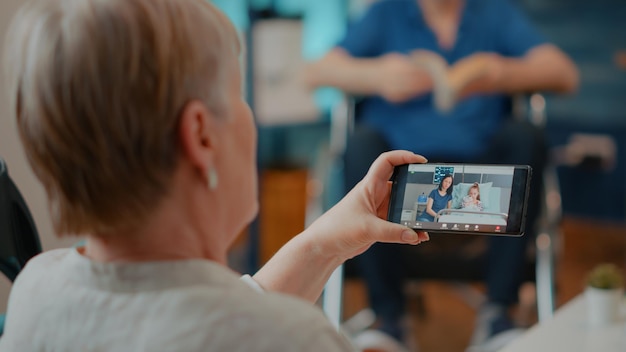 Free Photo grandmother using online conference call to chat with relatives on mobile phone. retired adult talking on remote videoconference with daughter and niece, doing telecommunication.