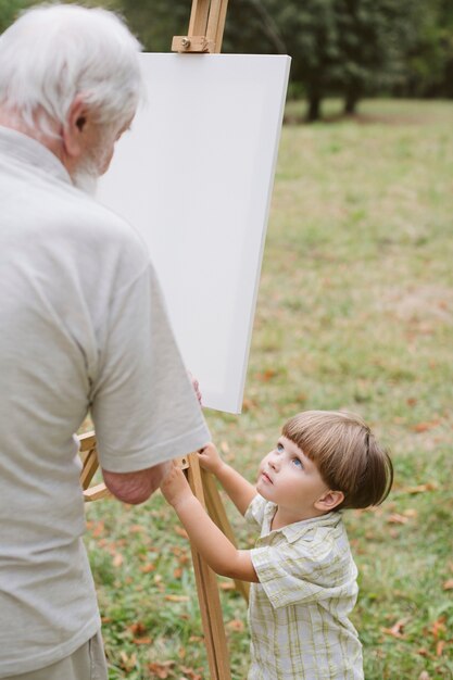 Grandpa painting and grandson watching