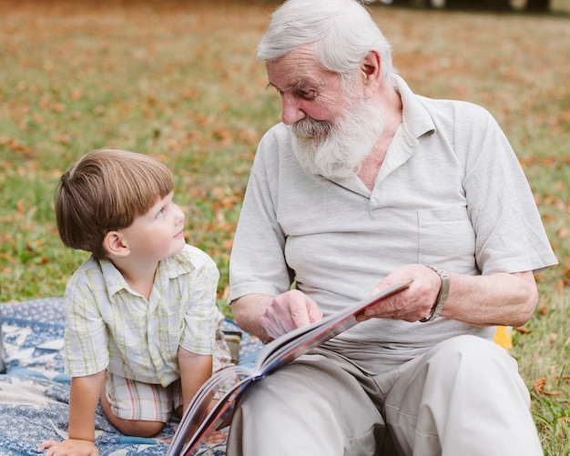 Free photo grandpa reading for grandson in park