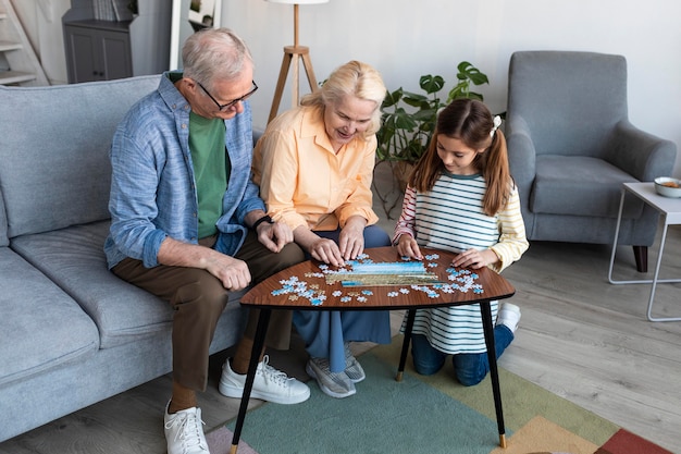 Grandparents and girl doing puzzle full shot