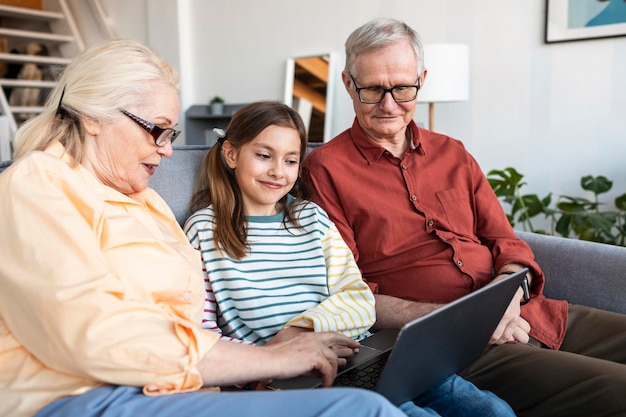 Free photo grandparents and girl with laptop