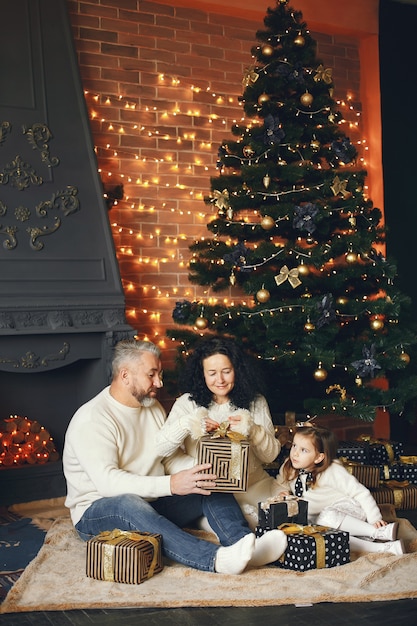 Grandparents sitting with their granddaughter. Celebrating Christmas in a cozy house.