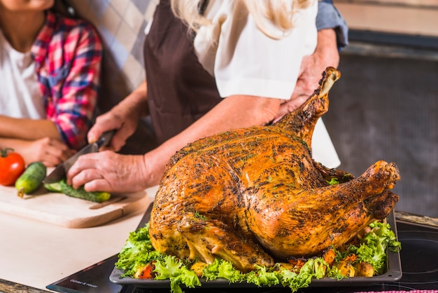 Grandparents with granddaughter cooking turkey 