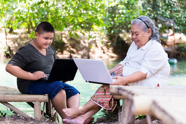 Grandson teaching his elderly female use laptop