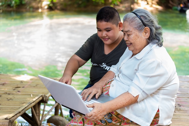 Free photo grandson teaching his elderly female use laptop