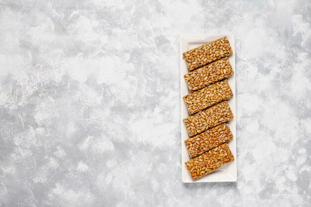 Granola bar. Healthy sweet dessert snack. Sesame, peanut, sunflower in honey. Gozinaki is Georgian national food, oriental sweet. Top view on concrete 