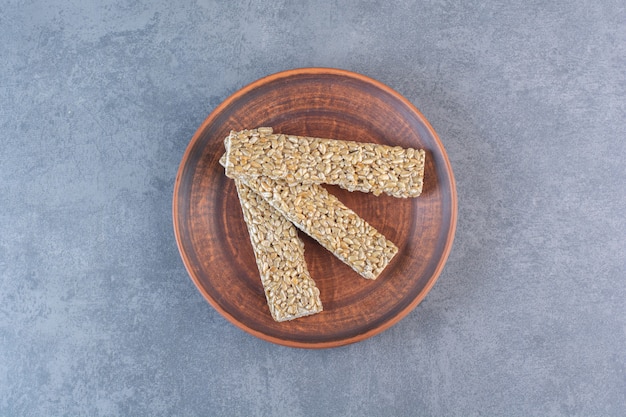 Free photo granola bars in a wooden plate , on the marble surface