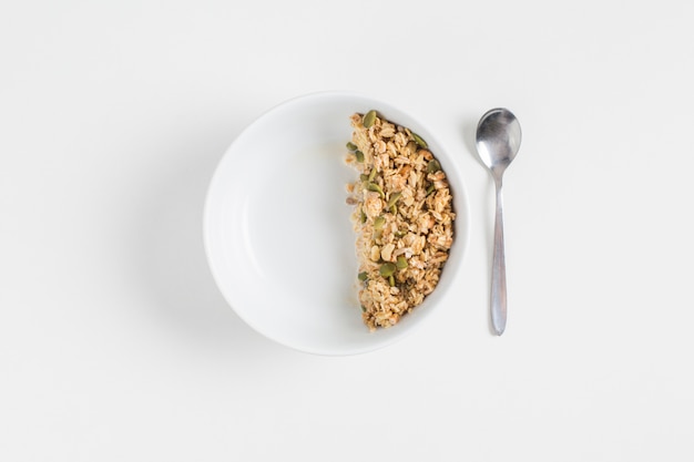 Free Photo granola with pumpkin seeds in white bowl and spoon on white background