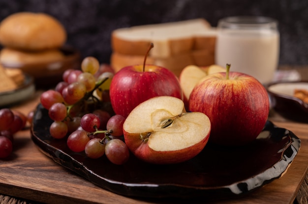 Grapes, apples and bread in a plate on the table