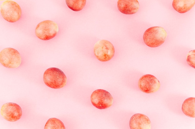 Grapes randomly spread over pink surface