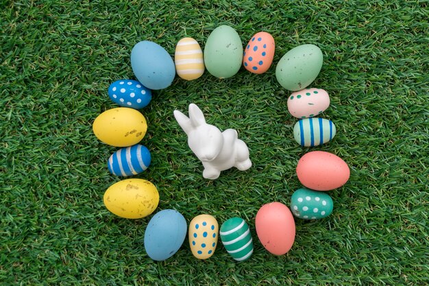 Grass background with easter bunny surrounded by colored eggs