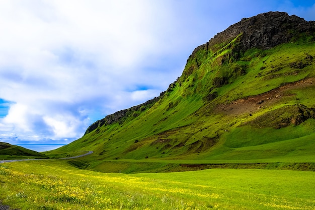 Free Photo grassy field near a grassy mountain under a cloudy sky