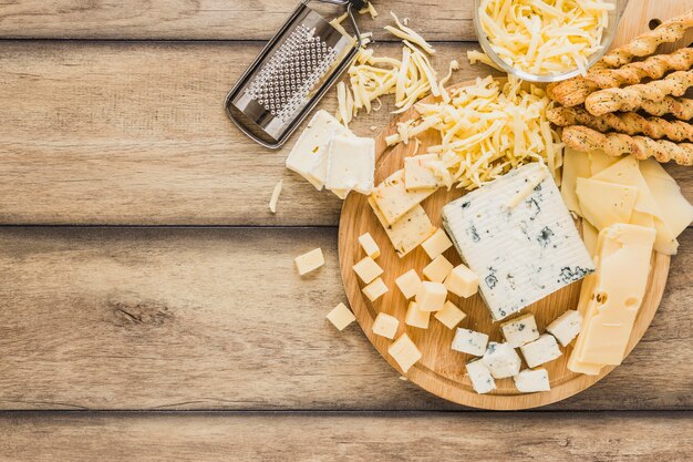 Grated cheese, cheese blocks and bread sticks over the desk