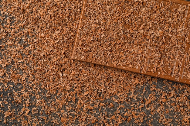 Grated chocolate with choco bar flat lay on a dark background