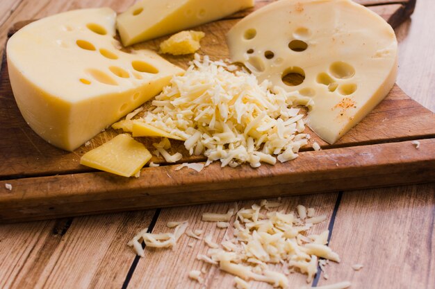 Grated and slices of emmental on chopping board over the table