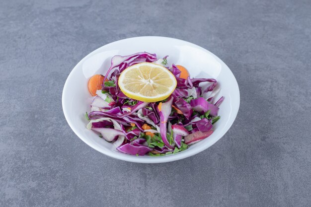 Grated vegetables with lemon on the plate, on the marble surface.