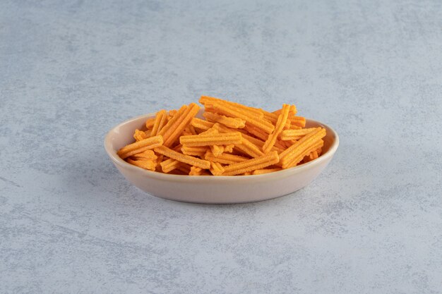 Gray bowl of crispy crackers placed on stone background.