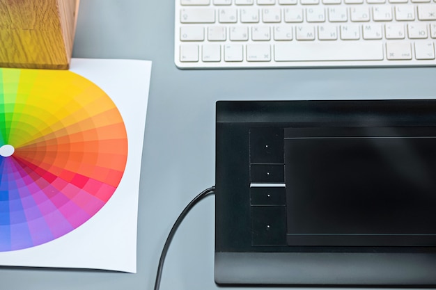 Free Photo the gray desk with laptop, notepad with blank sheet, pot of flower, stylus and tablet for retouching