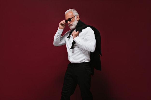 Free photo gray haired man in black pants and white shirt holds jacket