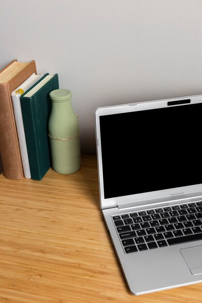 Gray laptop with books on wood desk