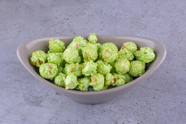 Gray oval bowl with flavorous candy coated popcorn on marble background. High quality photo