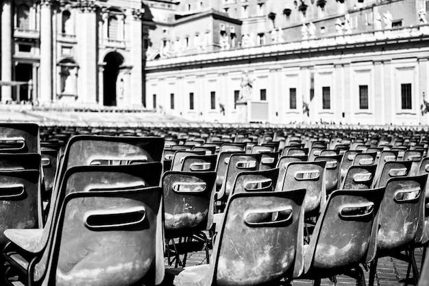 Free Photo gray scale shot of black plastic chairs in a square in rome