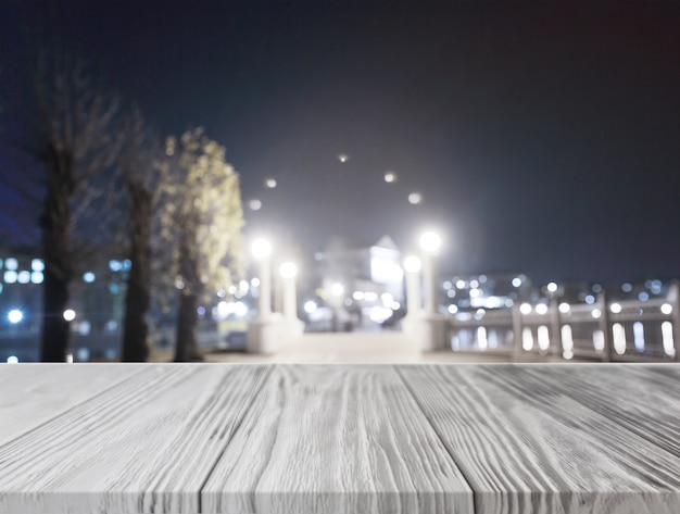 Free Photo gray wooden desk in front of illuminated city at night