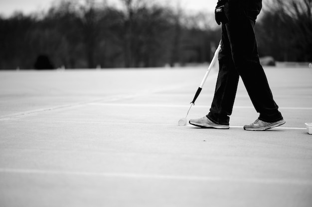 Free photo grayscale of a man painting lines on a parking lot