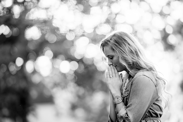 Free photo grayscale, selective shot of a blonde female praying