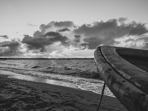 Free Photo grayscale shot of a boat front on a beach with large waves