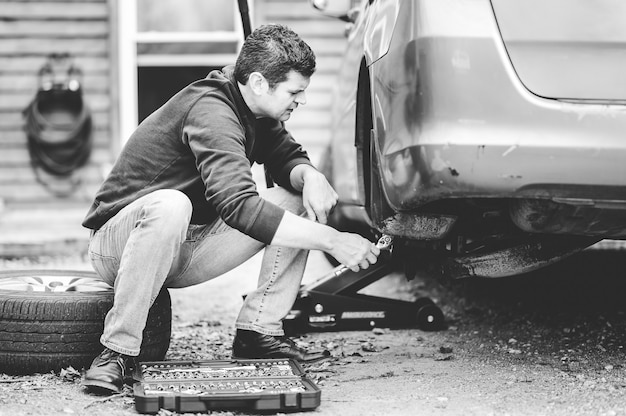 Free photo grayscale shot of a man repairing a wheel