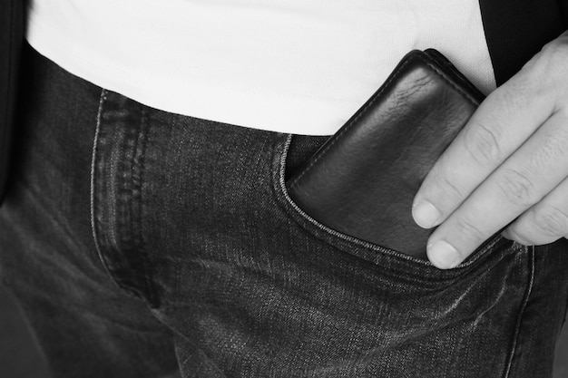 Free Photo grayscale shot of a person putting a leather wallet in his pocket