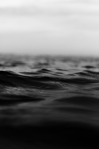 Grayscale vertical shot of tiny rough sea waves