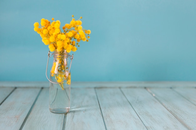 Free photo great background with wooden surface, vase and yellow flowers