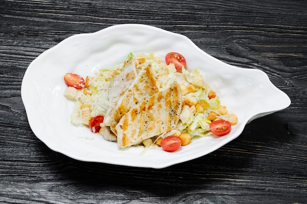 Free Photo greek caesar salad with white meat, lettuce and cherry tomatoes inside white plate.