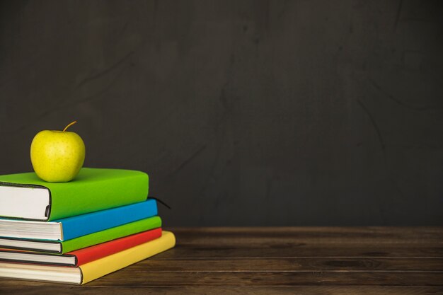 Green apple on book pile