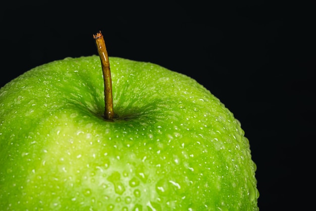 Free photo green apple in drops of water on a black background isolated