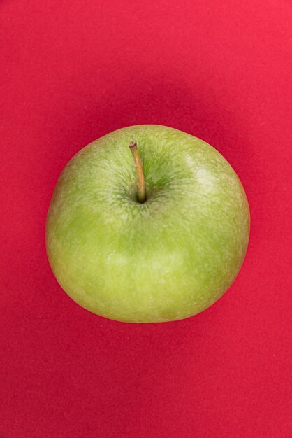 Green apple on the red background